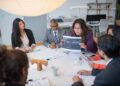 A boardroom table split between AI pilots still running in isolation and AI systems already integrated across functions, illustrating a governance screen for AI investment