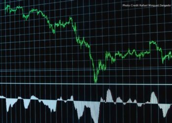 A trading floor screen showing four company earnings headlines with record profit figures alongside falling stock price charts